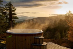 Bain nordique en bois fumant face à la campagne au lever du soleil