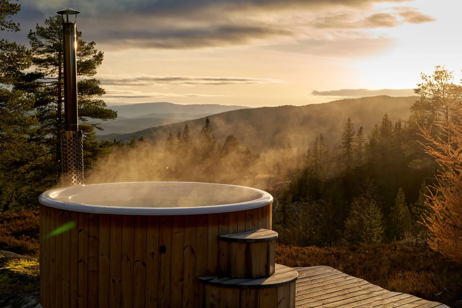Bain nordique en bois fumant face à la campagne au lever du soleil