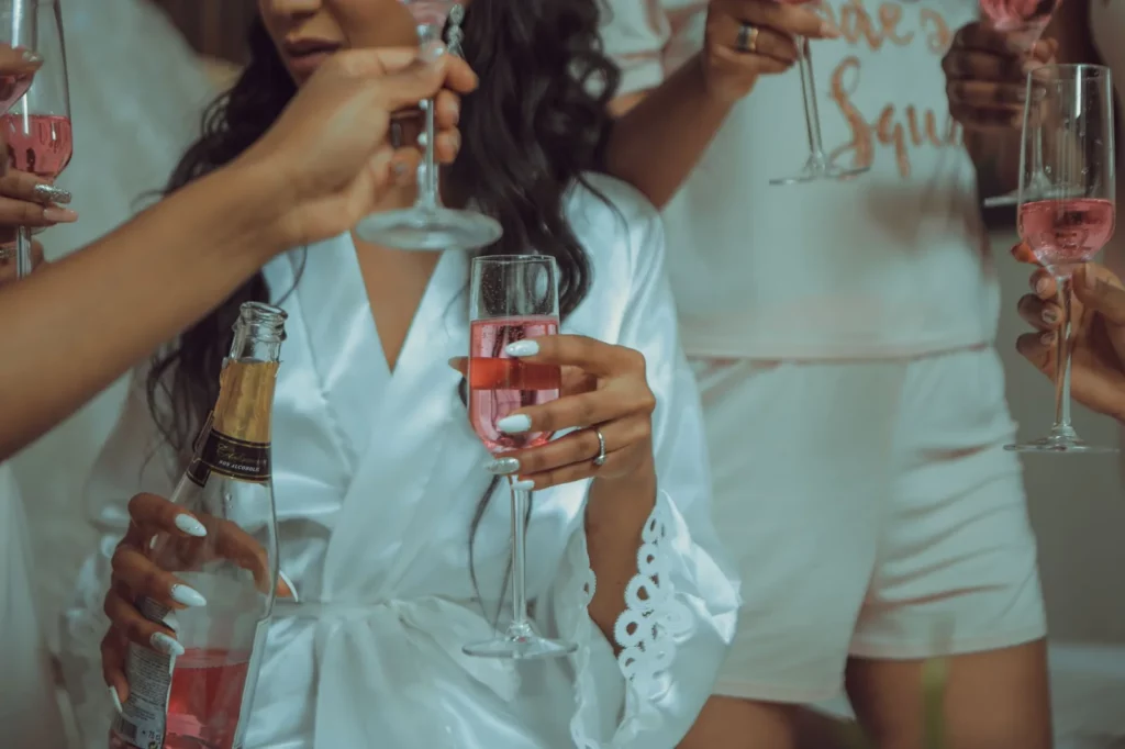 Amies en peignoir blanc trinquant au champagne rosé pendant les préparatifs