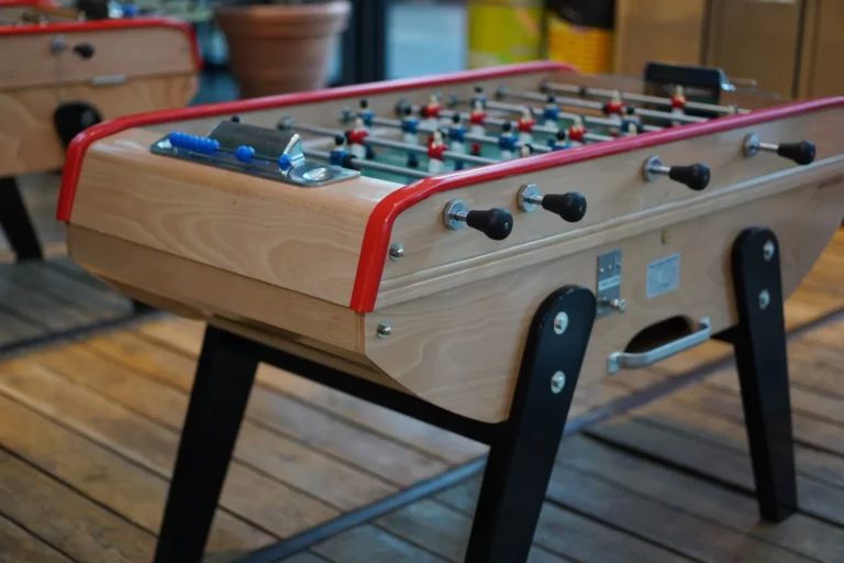 Baby-foot en bois aux poignées noires sur un parquet