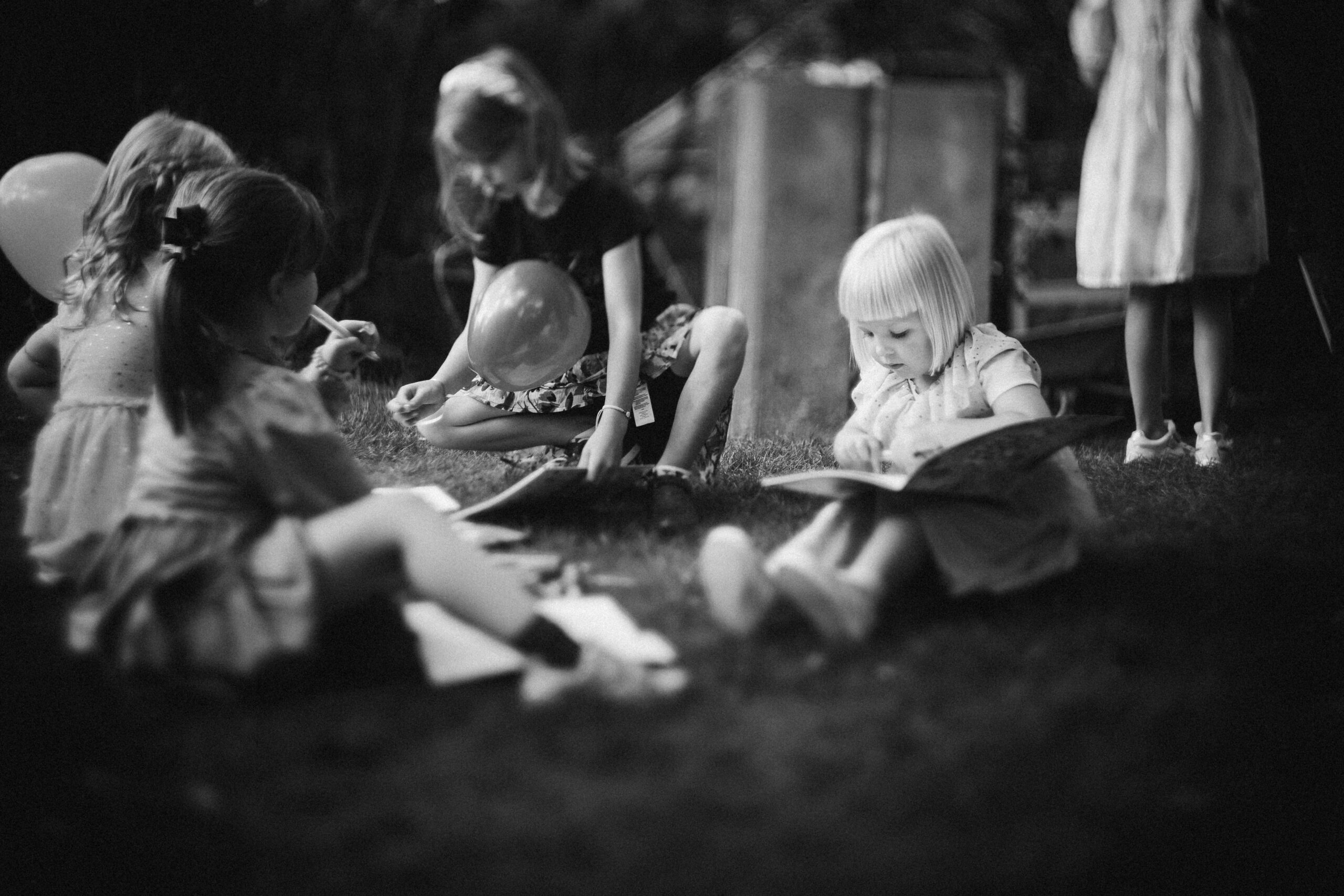 Groupe d'enfants assis en plein air lors d'une séance de lecture, photo en noir et blanc