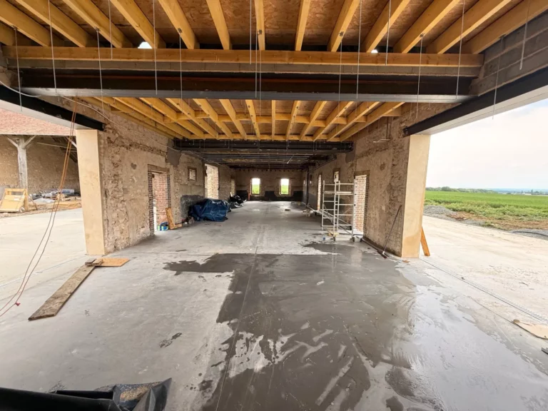 Dalle de béton coulée dans l'espace de réception, murs en pierre et poutres apparentes