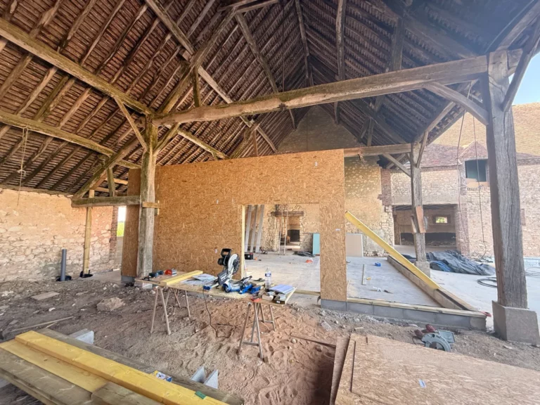 Salle festive en chantier sous la charpente ancienne de la grange, cloisons en bois en cours de pose